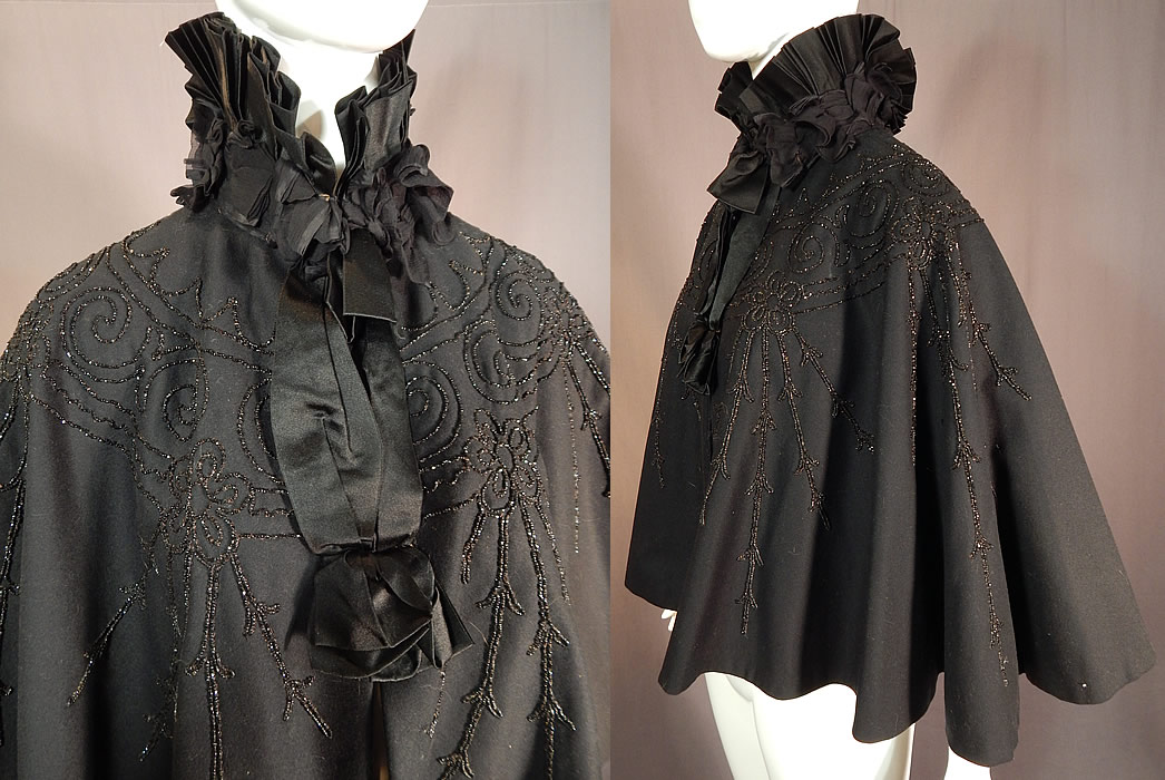 Victorian Black Wool Jet Beaded Pleated Silk High Neck Collar Winter Cloak Cape
This antique Victorian era black wool jet beaded pleated silk high neck collar winter cloak cape dates from 1890. It is made of a black wool fabric, with jet beading done in decorative spiral scrolling, floral vine designs and a black silk pleated high neck collar with black sheer chiffon ruched gathered trim edging. 