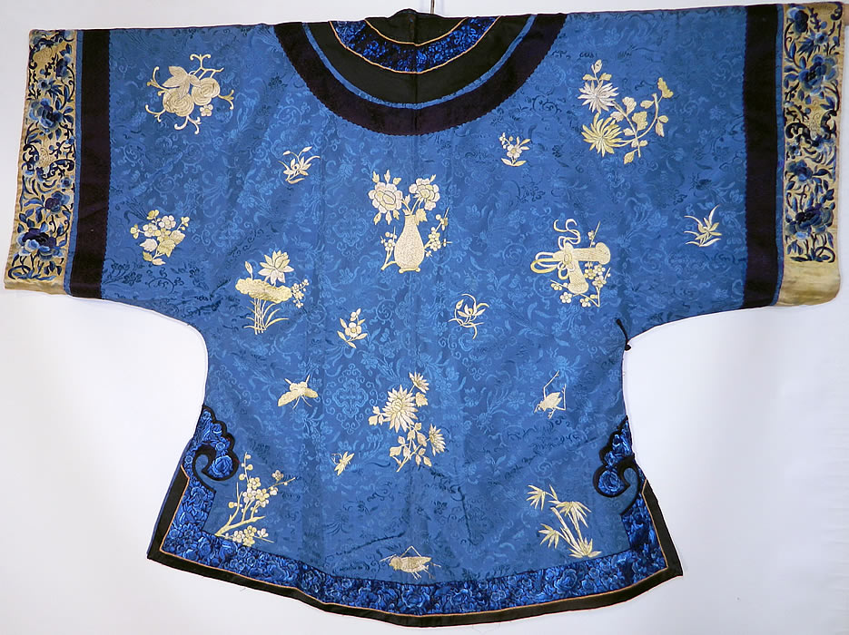 Antique Chinese Blue Silk Embroidered Insect Gourd Peach Floral Longevity Robe. There is black and black embroidered and silk trim edging, collar, with chartreuse yellow silk blue embroidered wide sleeve band cuffs, with butterflies and peony flowers.