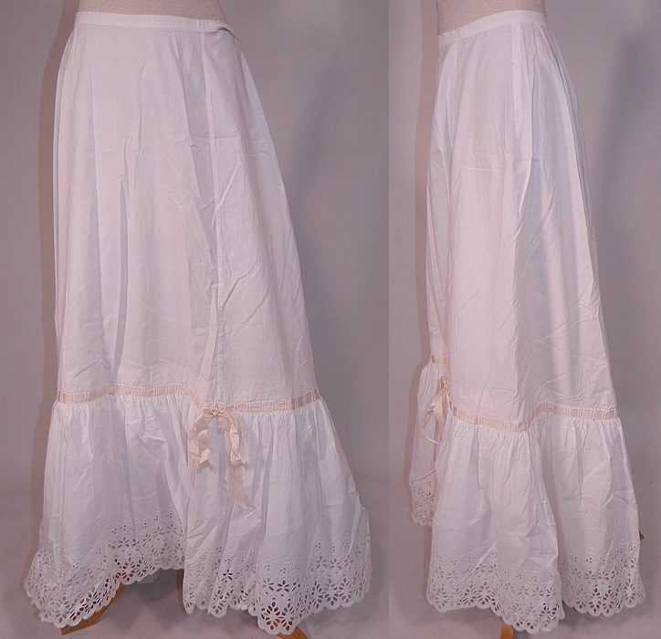 Victorian White Cotton Broderie Anglaise Eyelet Embroidery Cutwork Lace Petticoat Skirt
This antique Victorian era white cotton broderie anglaise eyelet embroidery cutwork lace petticoat skirt dates from 1880. It is made of a white heavy quality cotton fabric, with a broderie anglaise eyelet embroidery cutwork whitework lace scalloped bottom ruffle hemline and cream silk ribbon bow trim woven through it. 