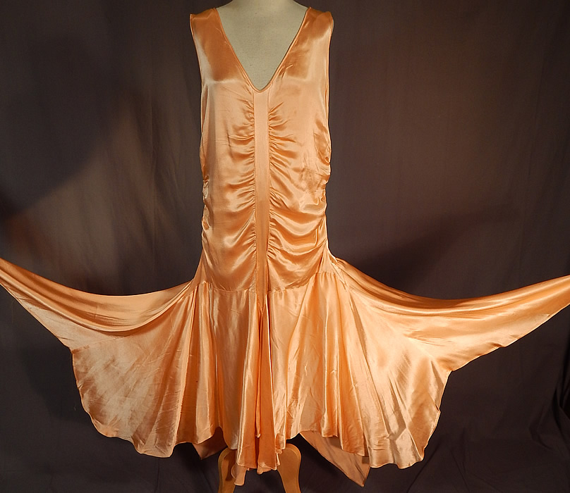 Vintage Peach Silk Satin Charmeuse Handkerchief Hem Skirt Drop Waist Flapper Dress
This vintage peach silk satin charmeuse handkerchief hem skirt drop waist flapper dress dates from the 1920s. It is made of a lustrous pastel peach color silk satin charmeuse fabric, with ruched gathering down the top and sides.