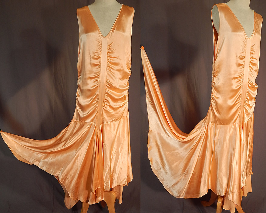 Vintage Peach Silk Satin Charmeuse Handkerchief Hem Skirt Drop Waist Flapper Dress
This fabulous flapper drop waist dress is sleeveless, with plunging V necklines, ruched gathering going down the front, back and sides, an uneven asymmetrical handkerchief hemline full skirt, longer along the sides, side snap closures and has a net lined camisole top.