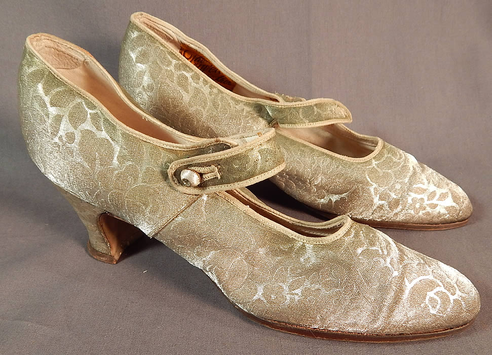 Vintage Traveler Shoe Art Deco Silver Lamé Lame Brocade Mary Jane Button Strap Shoes
This pair of vintage Traveler Shoe Art Deco silver lamé brocade Mary Jane button strap shoes date from the 1920s. They are made of a silver metallic lamé damask weave brocade fabric, with a woven floral rose leaf pattern design.