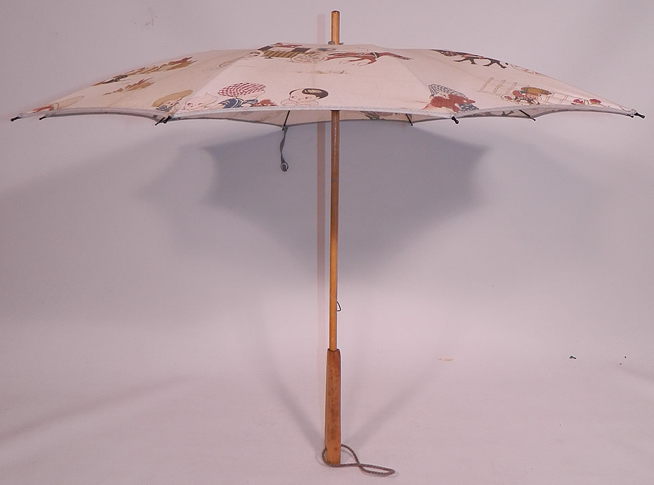 Vintage Chloe Preston Childrens Kewpie Illustration Print Linen Parasol
There is a wooden handle and finial top with blue gathered scrunchie fabric trim, button strap closure and blue rope strap attached to the bottom handle for carrying.