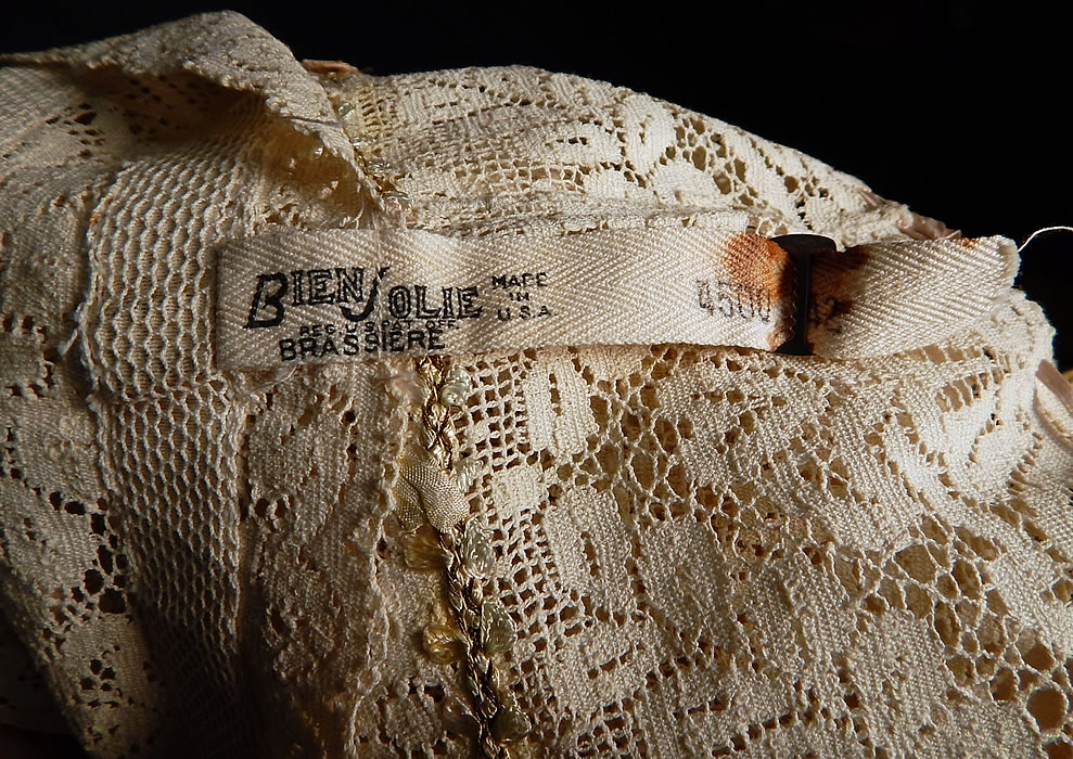 Vintage Bien Jolie Brassiere White Filet Lace Rosette Camisole Bra Bandeau Top
There is a "Bien Jolie Brassiere Made in U.S.A." Size 42 stamped label strap hanging down the front. The bra measures 18 inches long, with a 36 inch bust and 36 inch waist. It is in good as-is condition, with some frays along the ribbon shoulder straps. This is truly a wonderful piece of wearable lingerie art!