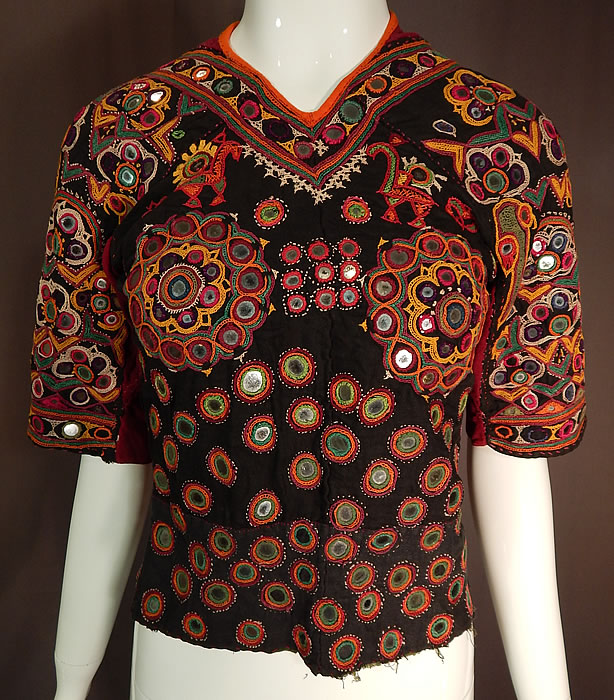 Vintage Indian Gujarati Kutch Work Embroidered Mirror Choli Boho Blouse Top
This vintage antique Indian Gujarati kutch work colorful embroidered mirror choli boho blouse top dates from the early 1900s. It is hand stitched, made a hand dyed black, red cotton twill fabrics with vibrant colorful decorative crewel chain stitch kutch work embroidery done in the tribal folk patterns from Gujarati, Rajasthan India and Sindh Pakistan.