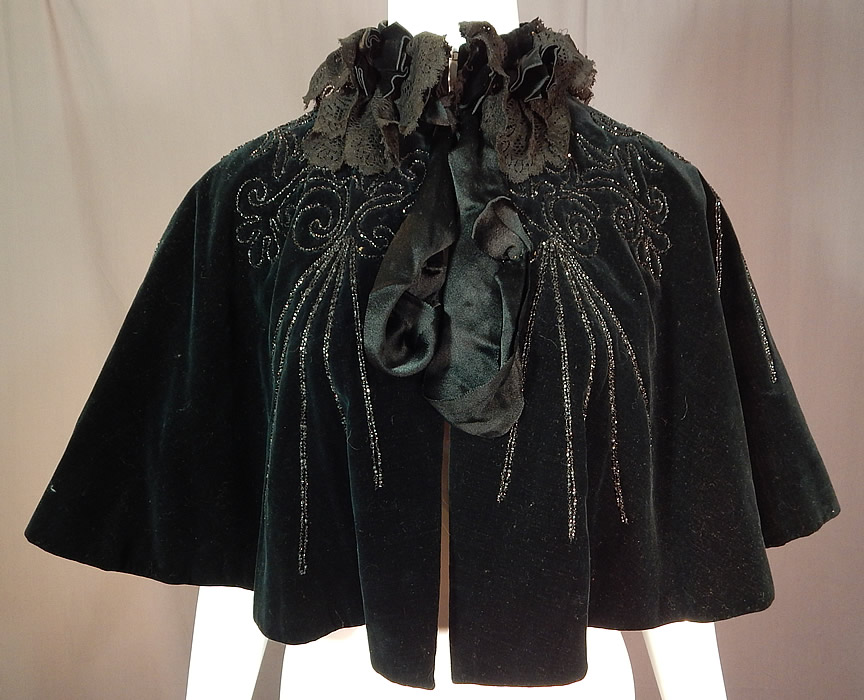 Victorian Midnight Blue Velvet Jet Beaded Lace Trim Cloak Cape Capelet
This antique Victorian era midnight blue velvet jet beaded lace trim cloak cape capelet dates from 1890. It is made of a dark midnight blue velvet fabric, with jet beading, black lace and ribbon trim edging the neckline.