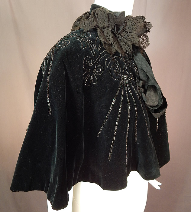 Victorian Midnight Blue Velvet Jet Beaded Lace Trim Cloak Cape Capelet
This beautiful beaded short cropped cloak cape capelet has a black lace ruffle collar, with hook closures on the front neckline and is fully lined in an iridescent burgundy red silk fabric. 