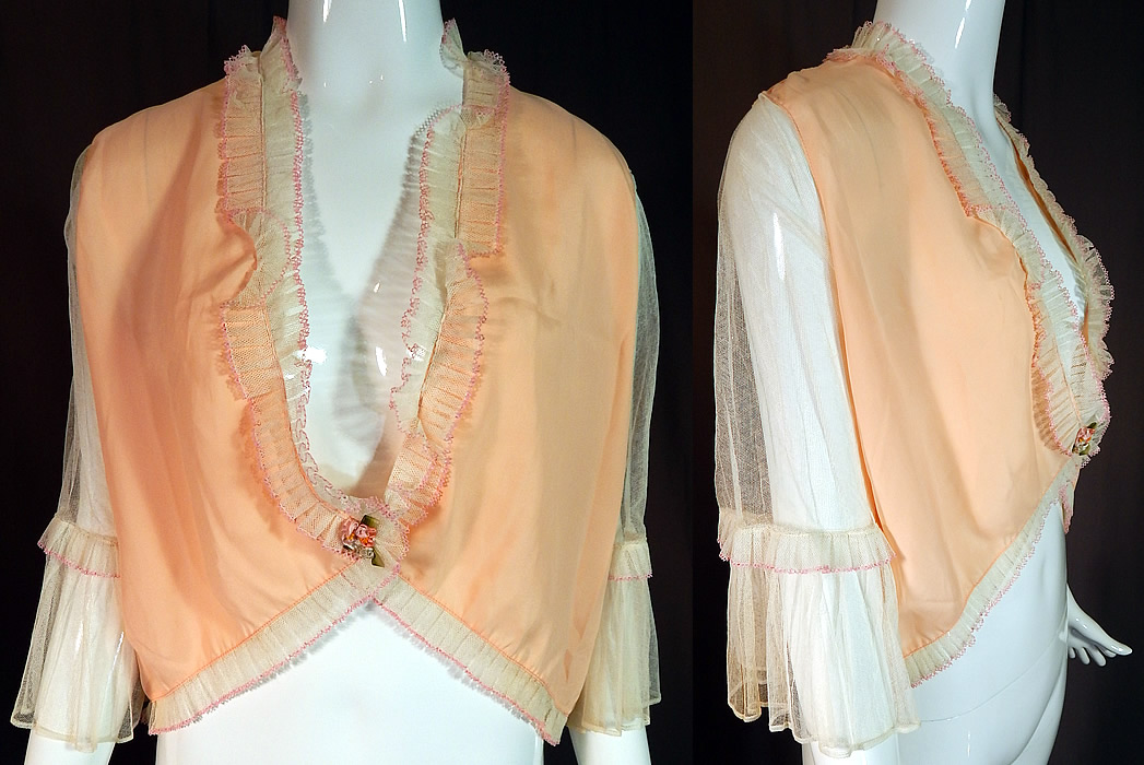 Vintage Pink Silk White Ruffle Rosette Trim Lingerie Boudoir Bed Jacket
This vintage pink silk white ruffle rosette trim lingerie boudoir bed jacket dates from the 1930s. It is made of a pastel pinkish peachy color silk fabric with sheer white net sleeves and pleated ruffle trim accented with pink crochet lace edging. There is a pastel silk ombre ribbon work trim on the front waist.