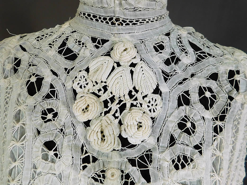 Victorian White Battenburg Tape Lace Crochet Trim Bodice Blouse Top
This antique Victorian era white battenburg tape lace crochet trim bodice blouse top dates from 1900. It is made of a white sheer hand made battenburg tape lace with connecting thread picot ornamented bars, buttonhole stitches, decorative pinwheel spiral, scrolling, striped designs and Irish crochet raised three dimensional trim flowers, leaves on the front yoke.