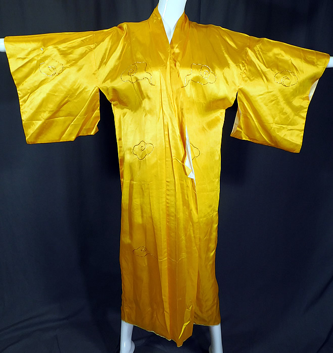 Vintage WWII Japanese Gold Couching Embroidery Dragon Yellow Kimono Robe
There are gold embroidered smoke clouds on the front, sleeves and a large dragon on the back looking down on Mount Fuji, a pagoda temple shrine and boat. This WWII souvenir Japanese dragon kimono robe has wide kimono sleeves, an open front with no closure and is fully lined in a white fabric.