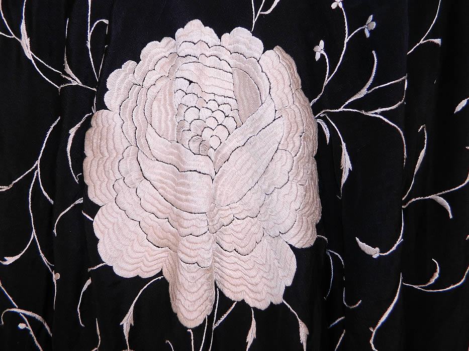 Antique Black & White Floral Silk Embroidered Canton Piano Shawl . There is a floral spiral vine leaf design, with four larger embroidered white roses in each corner. There is a fabulous hand knotted macramé black silk fringe which measures 20 inches long surrounding the entire shawl with rounded corners.