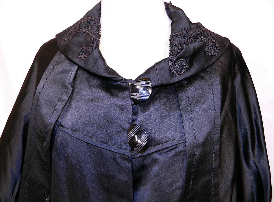 Vintage Black Silk Soutache Embroidered Opera Cloak Cape Coat Dress. It is made of a black silk satin fabric, with black silk raised soutache embroidery work and black velvet applique cutwork trim done in a decorative floral vine leaf design.