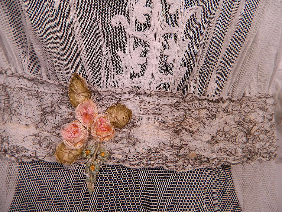 Edwardian White Net Tambour Embroidery Lace Silver Rosette Belted  Dress. There is a silver metallic lace, silk pastel ribbon rosette trim sash belt. This lovely lace long floor length dress has a layered flounce ruffle hemline, 3/4 length sleeves with lace ruffle trim cuffs, a belted sash waistband and hook closures down the back. 