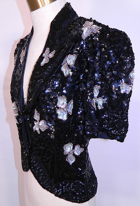Vintage Black Net Sequin Beaded Iridescent Gold Flowers Evening Jacket. It is made of a sheer black net fabric, completely covered with black sequins and an iridescent, gold beaded outlined flower pattern design.