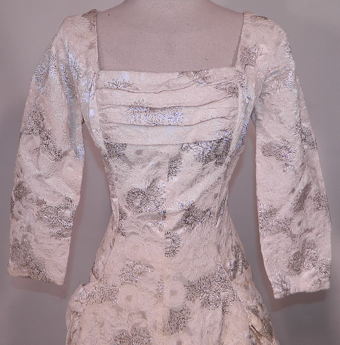 Vintage Vogue Couturier Design Silver Lame Brocade Sheath Dress Evening Gown Lam&eacute;. This gorgeous gown has a fitted wiggle sheath style, with a long full floor length skirt, squared front neckline, plunging V back, 3/4 length sleeves, a gathered drape bustle back skirt, back zipper closure and is fully lined. 
