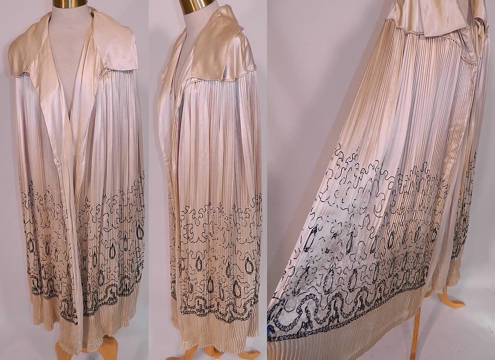 Vintage Art Deco Cream Silk Pleated Black Embroidered Evening Flapper Cloak Cape. This fabulous flapper evening opera cloak cape is a long mid length, loose fitting, has an open front with no closure, a fold over lapel collar and is fully lined in a cream silk fabric. The cape measures 45 inches long, 20 inches across the shoulders and is 75 inches in circumference.