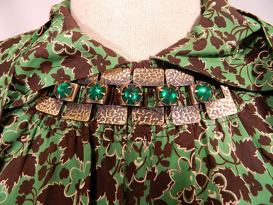 Vintage Green & Brown Grape Leaf Floral Print Silk  Day Dress Jeweled Necklace Trim. There is a textured gold tone brass metal chain link trim set with green gemstones sewn onto the front neckline in the style of a faux necklace. 