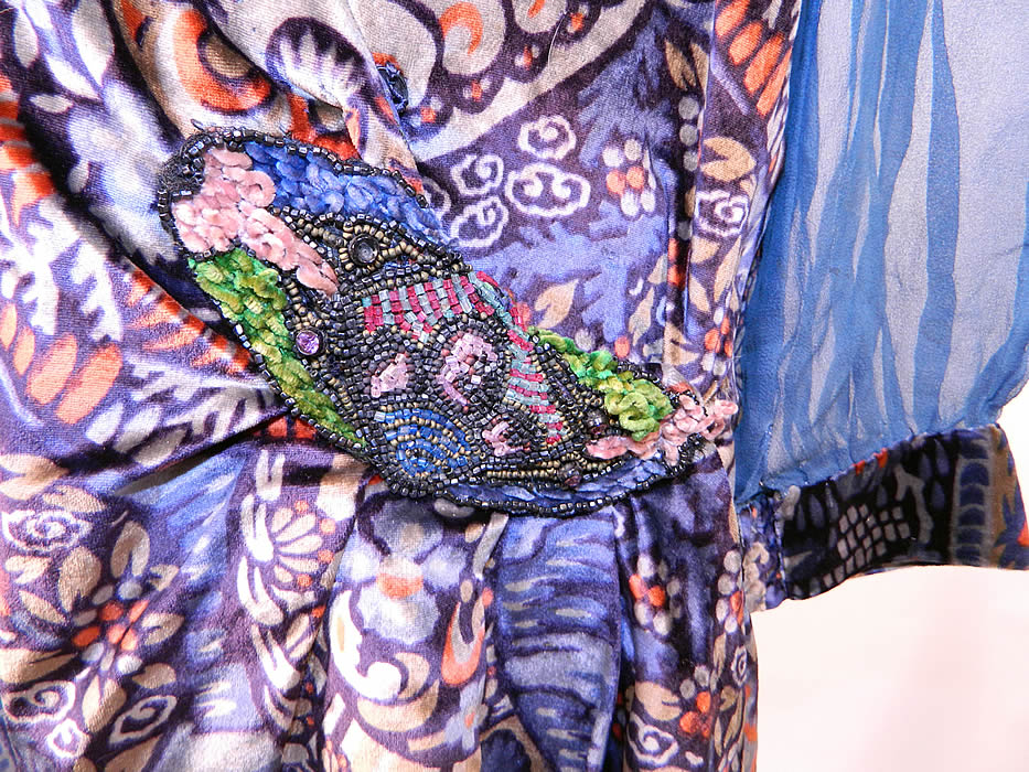 Vintage Embellished Colorful Blue Floral Print Velvet Drop Waist Flapper Dress. There are embellished trimmings, with an embroidered front neckline modesty insert panel, beaded chenille applique on the side hip and blue silk velvet cascading flower trim hanging down the front shoulder.