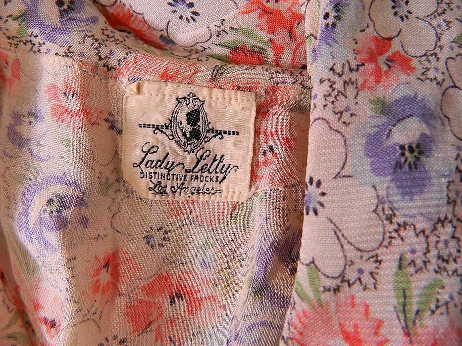 Vintage Lady Letty Distinctive Frocks Floral Print Cotton Day Dress Shift. This fabulous floral flapper day dress is loose fitting, with a drop waist straight shift style, a small ruffle shawl collar sleeveless top, with tiny blue velvet bows on the neckline, a long skirt with slight flared bottom and has a "Lady Letty Distinctive Frocks Los Angeles" label sewn inside. 