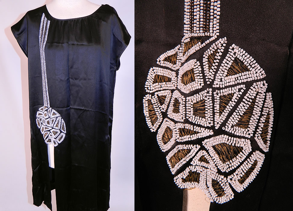 Vintage Art Deco Black Silk White Beaded Flapper Tunic Chemise Dress.
This Art Deco vintage black silk white beaded flapper tunic chemise dress dates from the 1920s. It is made of a black silk satin fabric, with white beading and gold metallic thread embroidery work done in an Art Deco abstract circular geometric pieced puzzle design along the front side.