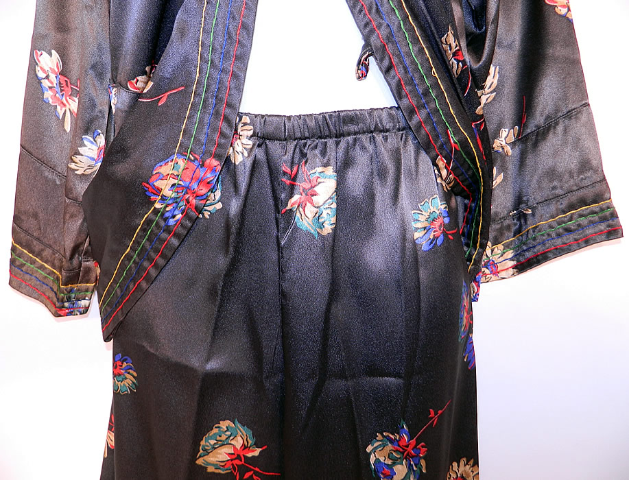Vintage Black Silk Satin Flower Print Pajamas Robe Jacket Pants Lounge Set
This pretty two piece pajamas lounging set has a mid length short robe style jacket top, with rainbow pin striped trim edging, a fold over front snap closure, long full sleeves and is unlined.
