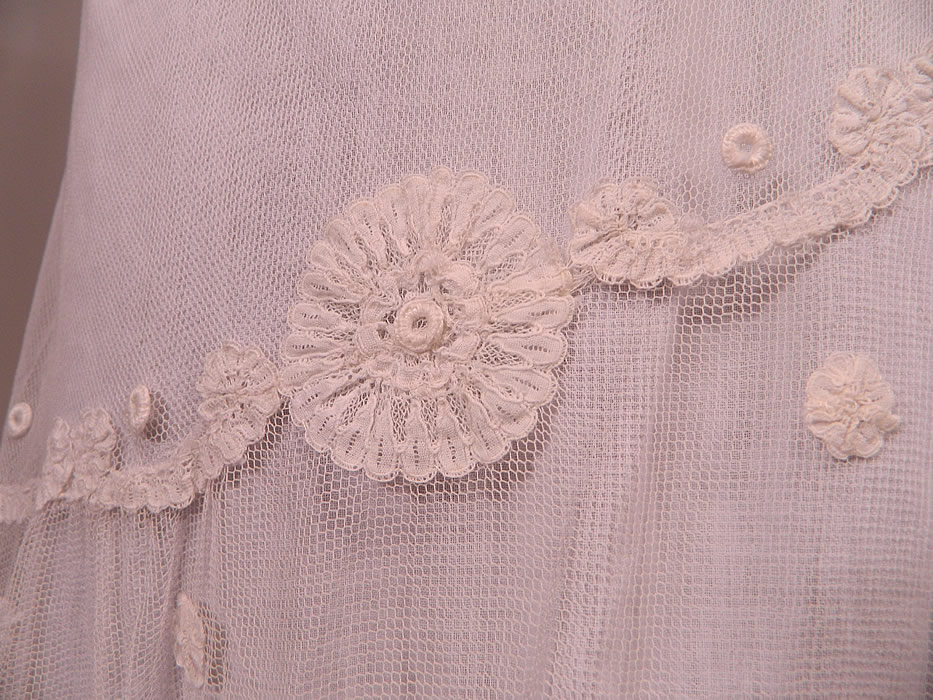 Vintage White Net Princess Tape Lace Applique Embroidered Drop Waist Dress & Slip
This lovely lace dress is loose fitting, with an asymmetrical drop waist, sleeveless. a large shawl style collar cape, with low scoop necklines, a handkerchief skirt hem and is sheer, completely unlined. 
