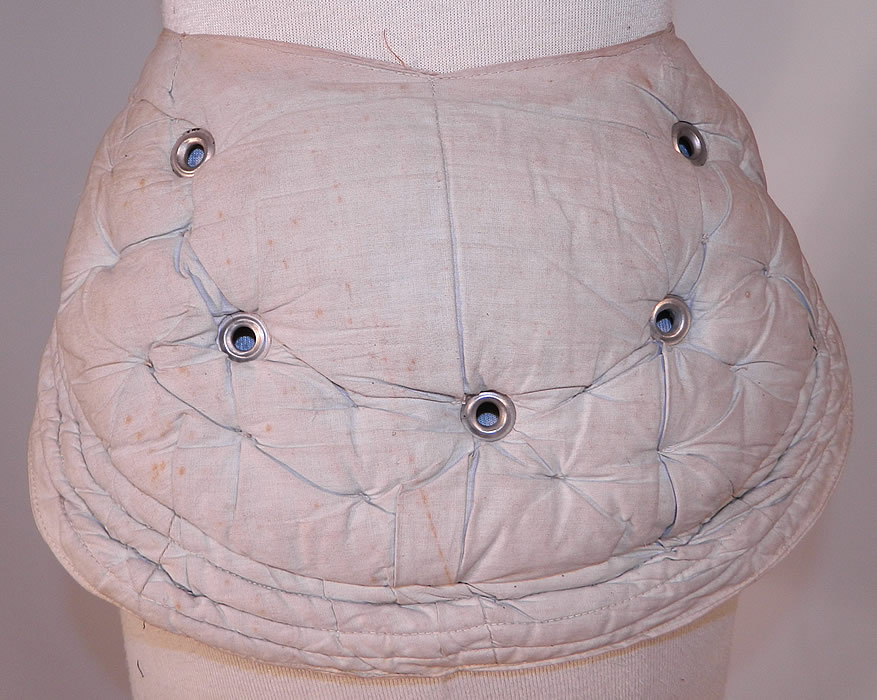Victorian Antique Grommet Bustle Quilted Cotton Pad Pillow Crescent Crinolette
This antique Victorian era Grommet bustle quilted cotton pad pillow crescent crinolette dates from 1880. It is made of a faded blue cotton fabric, stuffed with horse hair, quilted with silver metal grommets creating a puffed pillow crescent shaped bustle pad extender.