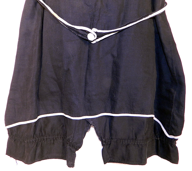 Vintage Black & White Cotton Belted Bathing Suit Swimsuit Dress & Bloomers
This fabulous flapper ladies bathing suit costume one piece swimsuit has a sleeveless style short tunic dress overlay with mother of pearl button closures on the shoulders, an attached belted tie sash with button front closure and short bloomer pantaloons pants sewn underneath, with gathered leg cuffs.