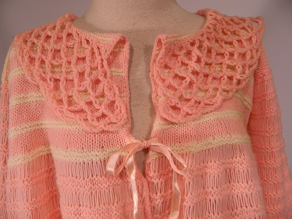 Vintage Hand Fashioned Ann Best Pink & White Knit Crochet Sweater Bed Jacket Top
This beautiful bed jacket style sweater top is loose fitting, with a flared bottom, large open lattice weave fold over round collar, long full sleeves with gathered scalloped cuffs, a pink silk ribbon tie front closure and is sheer, completely unlined. 