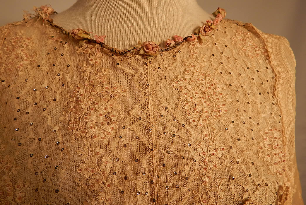 Edwardian Belle Epoque Cream Embroidered Net Lace Beaded Rosette Dress
This lovely lace dress is a long tea length, with a layered tiered peplum over skirt, silk lining underneath, 3/4 length sleeves, hook closures down the back and is lined in sheer net on top.