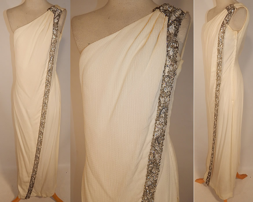 Vintage White Silk de Chine Silver Beaded One Shoulder Grecian Goddess Gown
This vintage white silk de chine silver beaded one shoulder Grecian goddess gown dates from the 1960s. It is made of an off white ivory color silk de chine fabric with a ribbed texture and silver, sequins, crystal bauble beaded trim along the side.