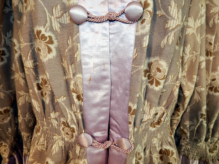 Edwardian Lavender Gray Floral Flannel Morning Robe Bed Jacket Coat
This marvelous morning robe bed jacket is a short mid length, with ruched gathering around the fitted peplum waist, long full sleeves with gathered silk trim cuffs, lavender silk covered button rope toggle closures down the front and is unlined.