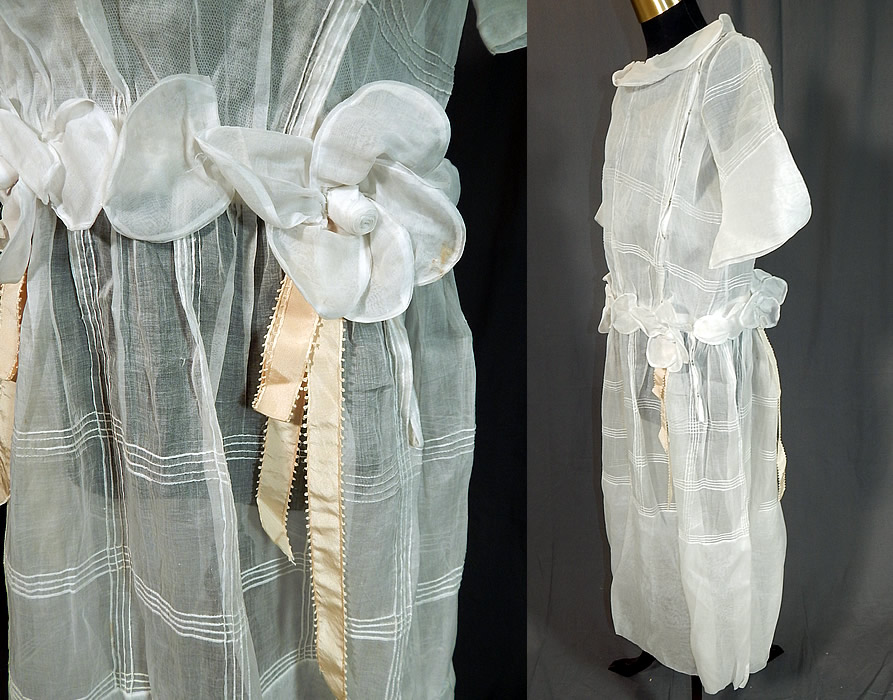 Vintage Windowpane White Organdy Rosette Ribbon Trim Drop Waist Dress
This pretty party dress has a drop waist, with a wide round Bertha style collar, full short sleeves, a rosette, ribbon trim attached belted waist, front top side snap closures and is sheer, lined only in the top with a cotton mesh net camisole.