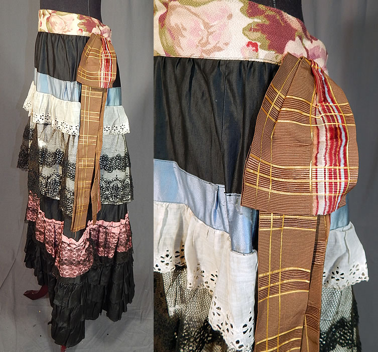 Victorian Black Cotton Ruffled Ribbon Lace Patchwork Petticoat Skirt Costume
This pretty petticoat skirt is a long full floor length, with layers of ruffles, a brown plaid silk ribbon bow trim accent side, blue patch pocket, replaced newer bark cloth floral fabric waistband, an open back with no closure, polished brown cotton, velvet trim dust ruffle hem underneath and is unlined. The skirt measures 40 inches long, with a 50 inch waist. 
