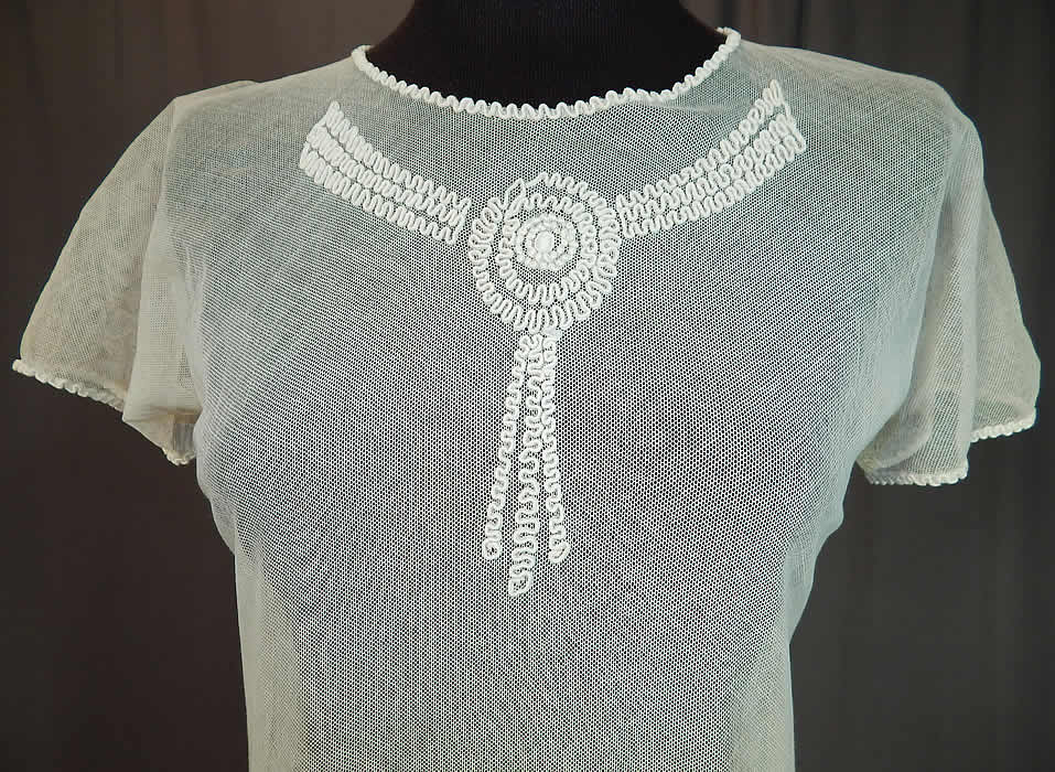 Vintage Girls White Sheer Tulle Net Soutache Ribbon Embroidery Drop Waist Dress
It is made of a white sheer tulle mesh net fabric with soutache ribbon embroidery work done in a raised garland scalloped circular rosette pattern design on the front neck and around the bottom skirt.