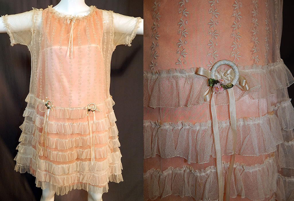 Vintage Embroidered Cream Net Lace Silk Ribbon Rosette Trim Peach Slip Dress
This vintage cream embroidered net lace silk ribbon rosette trim peach slip dress dates from the 1920s. It is made of an off white cream color sheer net fabric with embroidered floral vines on the top and cream silk ribbon bows and rosette ribbonwork garland wreath trim on the front waist.