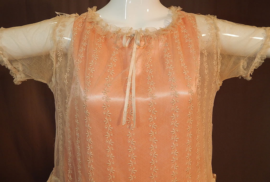 Vintage Embroidered Cream Net Lace Silk Ribbon Rosette Trim Peach Slip Dress
This lovely lace pretty party dress has a loose fitting drop waist style, with peach silk satin slip lining sewn inside, a ruffled ribbon drawstring neckline, short sleeves, a short skirt with tiered ruffles and a snap closure on the back neck. 