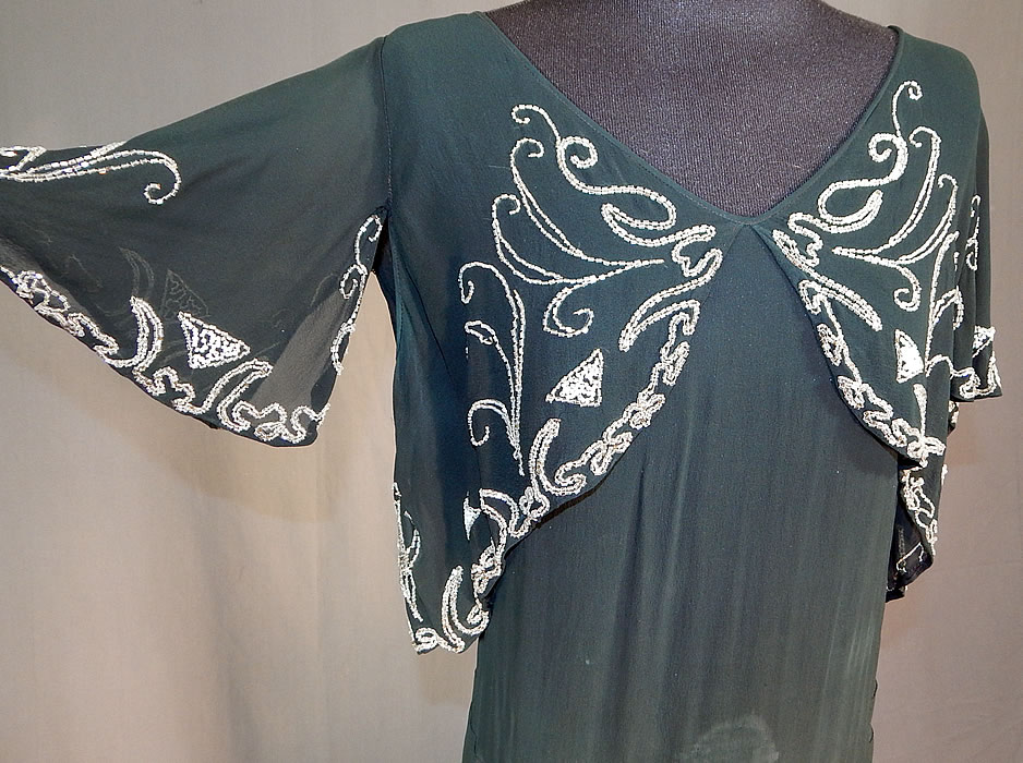 Vintage Black Silk Chiffon Butterfly Beaded Bias Cut Evening Gown Dress
This beautiful black bias cut evening gown dress has a form fitting sheath style, with a beaded overlay blouse cutaway short cropped top, V necklines, flared wide short sleeves, a long floor length skirt with side tiered ruffles and is sheer, unlined with no side opening.