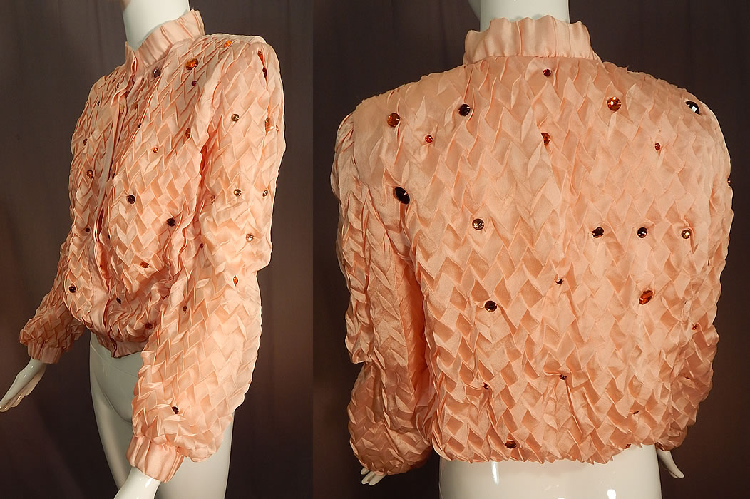 Vintage Krizia Martha Palm Beach Label Pink Silk Smocking Bejeweled Jacket
It is made of a pink pastel silk crepe de Chine fabric with smocking pleating throughout and varying sizes of colorful bejeweled beaded accents. This pretty pink jacket has a gathered elastic fitted waistband, cuffs, band collar, slight shoulder padding, long full sleeves, hidden buttons down the front for closure and is fully lined. 