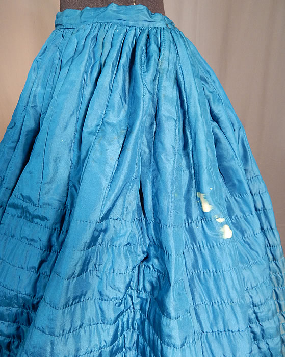 Victorian Bright Blue Silk Quilted Hand Stitched Winter Petticoat Hoop Skirt
The skirt measures 37 inches long, with a 26 inch waist and 100 inch circumference bottom. It is in good as-is condition, with only some small discoloration white bleach spots on the skirt and a small 1 inch split in the silk fabric near the bottom front (see close-ups). This is truly a rare blue color undergarment and wonderful piece of antique Victoriana wearable art!