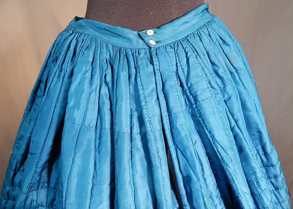Victorian Bright Blue Silk Quilted Hand Stitched Winter Petticoat Hoop Skirt
The skirt measures 37 inches long, with a 26 inch waist and 100 inch circumference bottom. It is in good as-is condition, with only some small discoloration white bleach spots on the skirt and a small 1 inch split in the silk fabric near the bottom front (see close-ups). This is truly a rare blue color undergarment and wonderful piece of antique Victoriana wearable art!