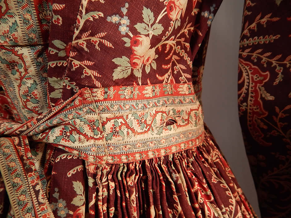Victorian Civil War Era Chintz Calico Hoop Skirt Morning Wrapper Gown Dress
This wonderful wrapper morning gown dress has a long floor length full hoop skirt (hoop not included underneath), with a round fold over collar, long full sleeves, tiny glass button closures all the way down the front, side skirt pocket, an attached belted tie sash and is fully lined in a contrasting brown reptile scale calico print cotton fabric inside. 