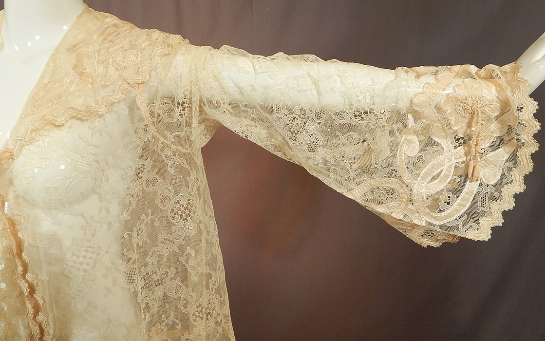 Victorian Blonde Chantilly Lace Cream Silk Applique Trim Bell Sleeve Coat Jacket
There are cream silk braided rope tassel trim accents on the sleeve cuffs, back collar, lappet tie ends and along the bottom. This lovely lace coat jacket has a loose fitting robe style, with a large shawl collar, long full pagoda bell shape flared sleeve cuffs, long lappet ties hanging down the front with a hook closure at the chest and is sheer, unlined. 