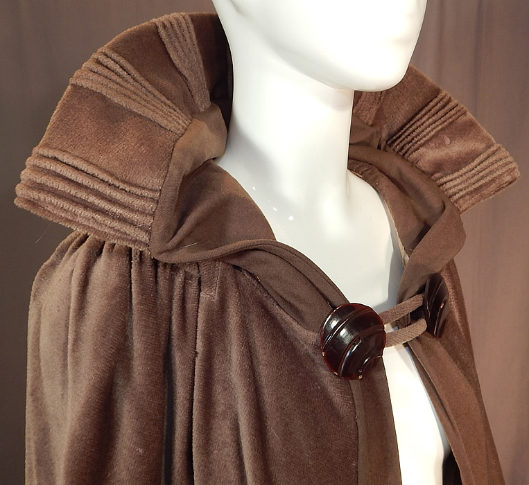 Vintage Art Deco Khaki Brown Mohair Wool Winter Shawl Collar Cloak Cape
This wonderful winter cloak cape is a long full floor length, with a wide shawl collar mixed with wool and pleated ribbed trim accents, two large carved celluloid brown button toggle closure on the front neck and is fully lined with a grayish taupe color silk lining and arms straps sewn inside. 