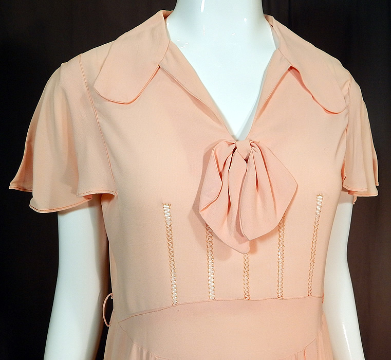 Vintage Pink Pastel Silk Crepe de Chine Drawn Work Cape Sleeve Day Dress
This pretty pink day dress has a mid length skirt with pleating along the bottom, a short cape sleeve, fold over rounded lapel collar, bow trim neckline, no side opening closures and is unlined. 