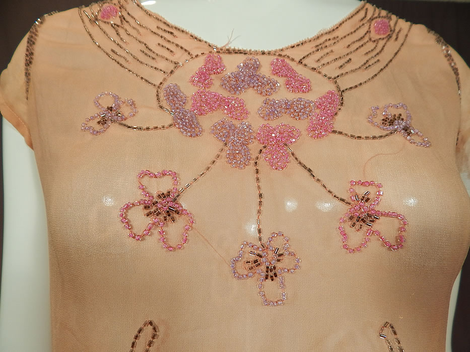 Vintage Art Deco Pink Silk Chiffon Lavender Floral Leaf Beaded Flapper Dress
This fabulous flapper dress has a fitted top, short cap sleeves, scalloped trimmed fitted waist, short full skirt, side snap closures and is sheer, unlined.