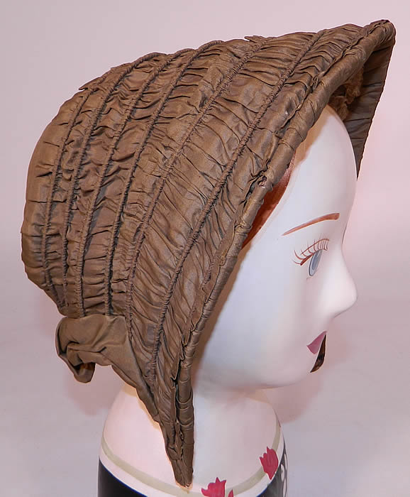 Victorian Civil War Green Silk Pleated Ruched Drawn Shirred Spoon Bonnet. It is hand stitched, made of a stiffened white buckram linen cloth, mesh net lining the inside, cane supports sewn into the channels, covered with a olive green color pleated ruched silk fabric, with tiny tucks and gathers.