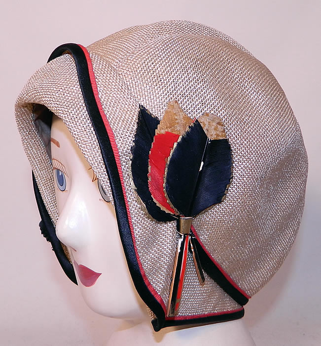 Vintage Flo Lill Art Deco Red, Black & White Straw Feather Flapper Cloche Hat.The hat is made of an off white woven straw fabric, with black and red silk ribbon edging and feather leaf trim on the sides.