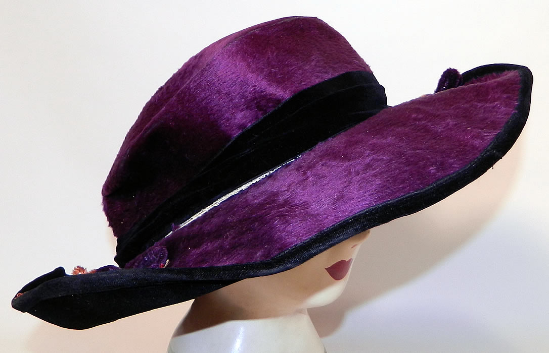 Edwardian Vintage Wolf Millinery Purple Velvet Flower Trim Wide Brim Hat. This pretty purple  plum hat has  an uneven asymmetrical oval shaped wired wide brim, which is wider along the sides and front, narrow in the back, with a black velvet backing underneath and a black silk lining inside the crown, with a "Wolf Millinery 216 N. Duke St. Lancaster, PA" label.