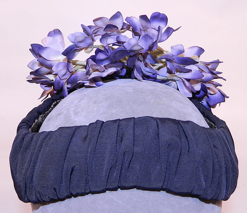 Vintage Black Silk Grosgrain Ribbon Purple Violet Flower Fascinator Hat
It is made of a gathered black silk grosgrain ribbon ribbed fabric covering the base and purple silk violet flowers bouquet hanging down the back.